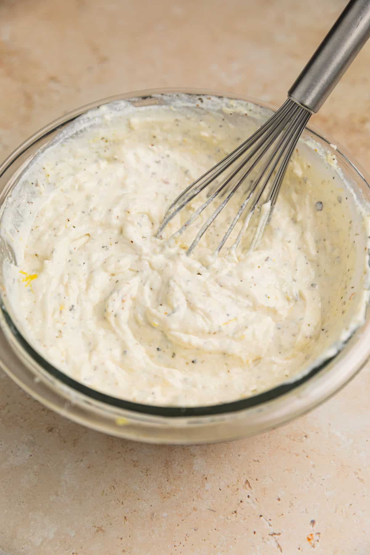 Lemon ricotta mixture in bowl with whisk.