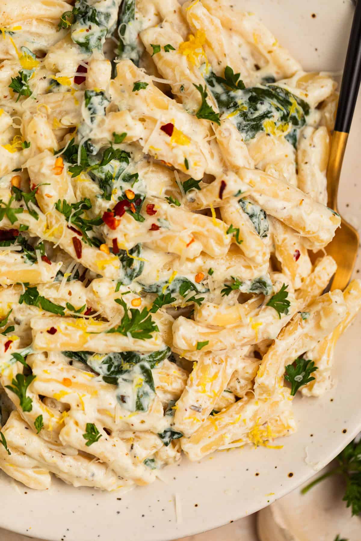Plate with lemon ricotta creamy pasta topped with chopped parsley and grated parmesan.