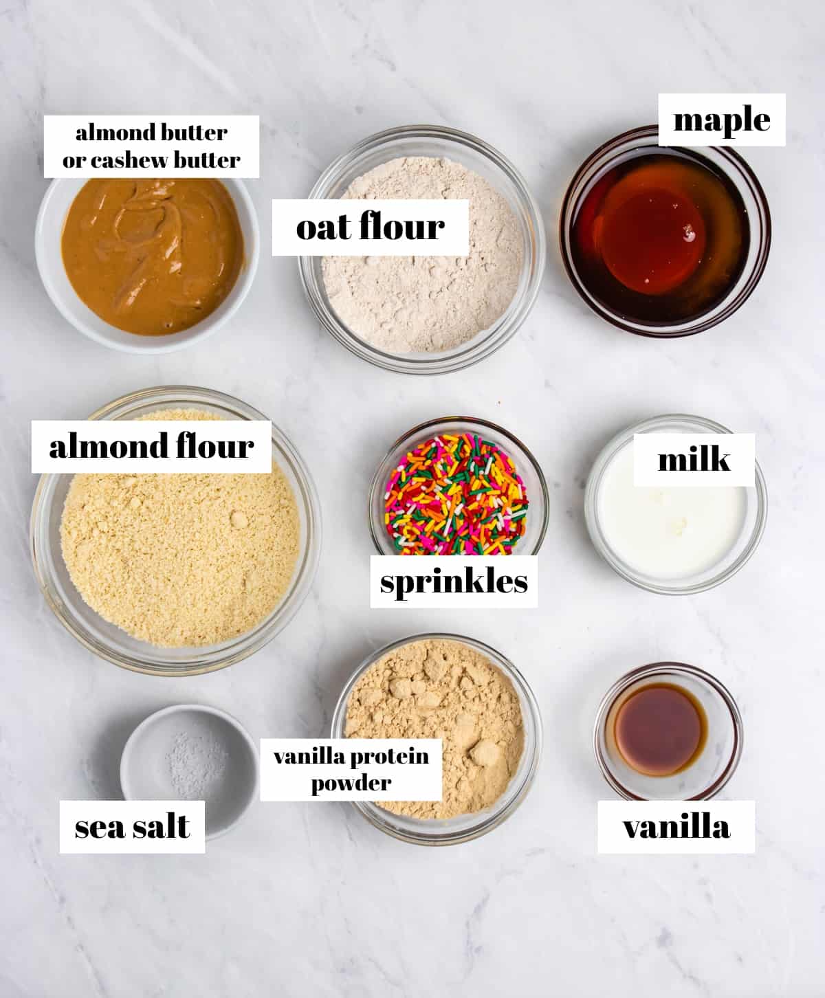 Almond flour, protein powder, maple syrup, sprinkles and other ingredients labeled on counter.