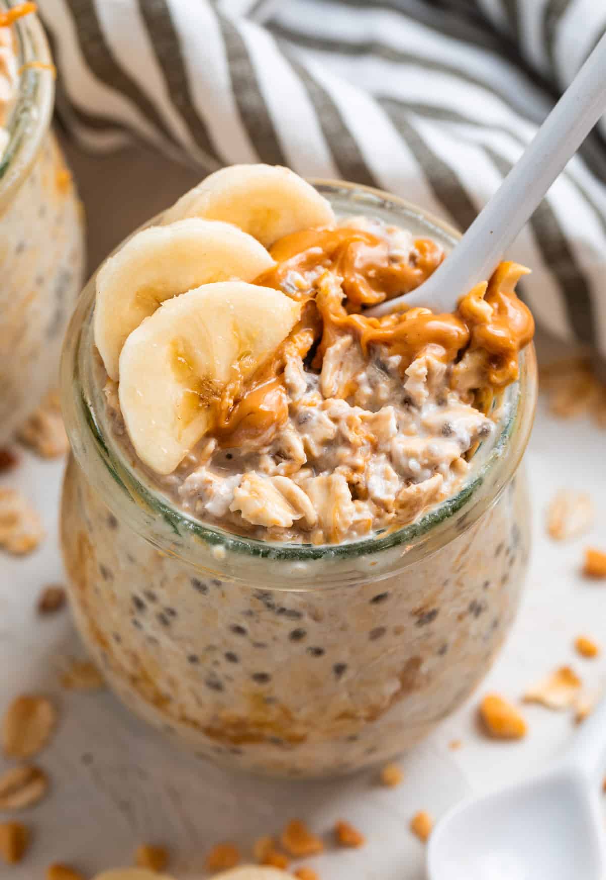 Spoon in jar of overnight oatmeal with peanut butter and banana.