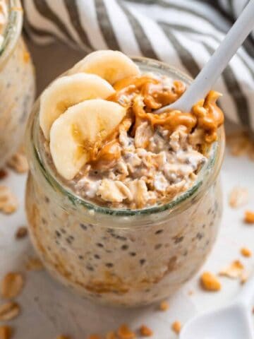 Spoon in jar of overnight oatmeal with peanut butter and banana.
