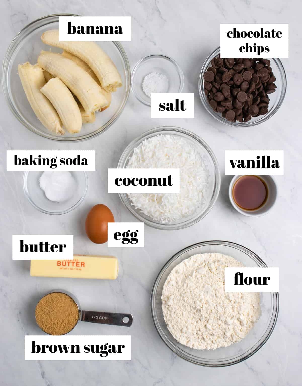 Flour, chocolate chips, banana, butter and other ingredients labeled on counter.