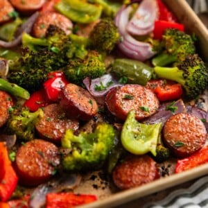 Sausages and peppers with broccoli on sheet pan after being cooked.