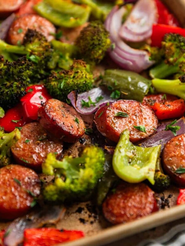 Sausages and peppers with broccoli on sheet pan after being cooked.