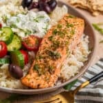 Baked salmon filet with oregano and Greek flavors on top of rice with feta, olives and other toppings.