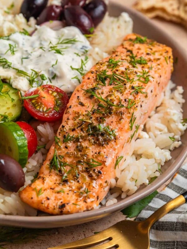 Baked salmon filet with oregano and Greek flavors on top of rice with feta, olives and other toppings.