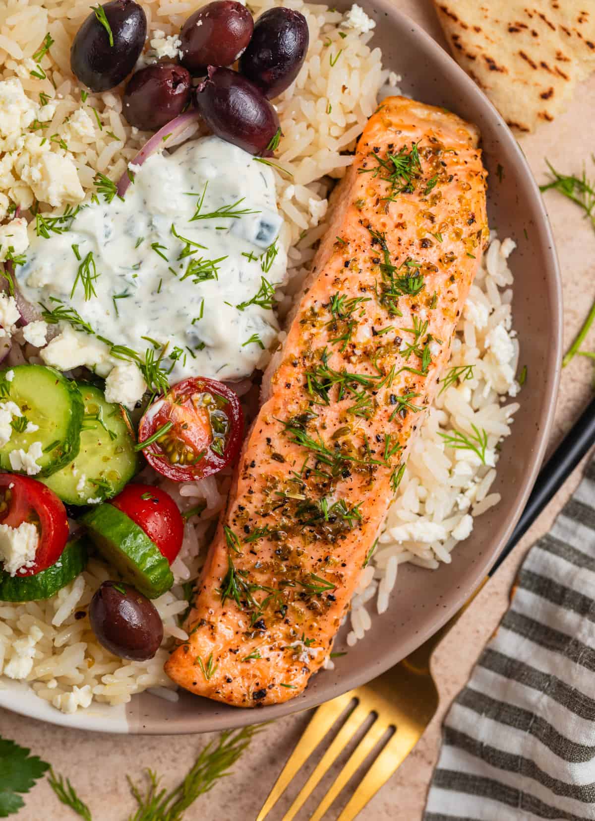 Overhead view of Greek salmon rice bowls with feta, kalamata olives, tomatoes, cucumbers and more.
