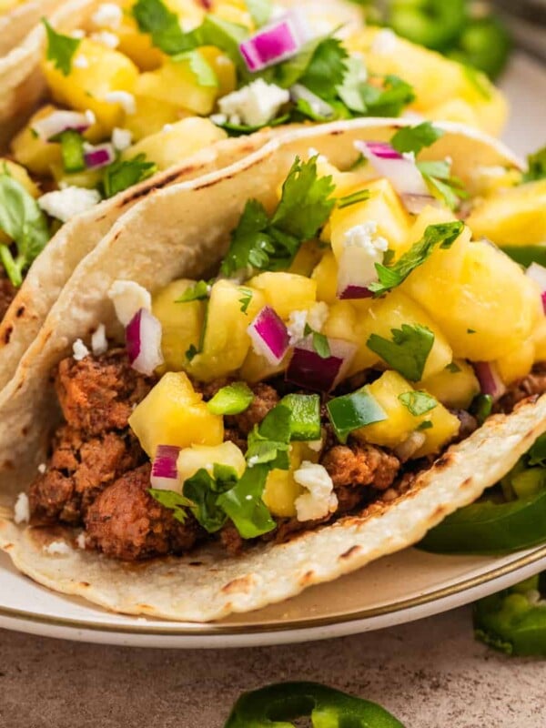 Ground pork tacos in tortillas topped with pineapple, jalapeño and cilantro salsa.
