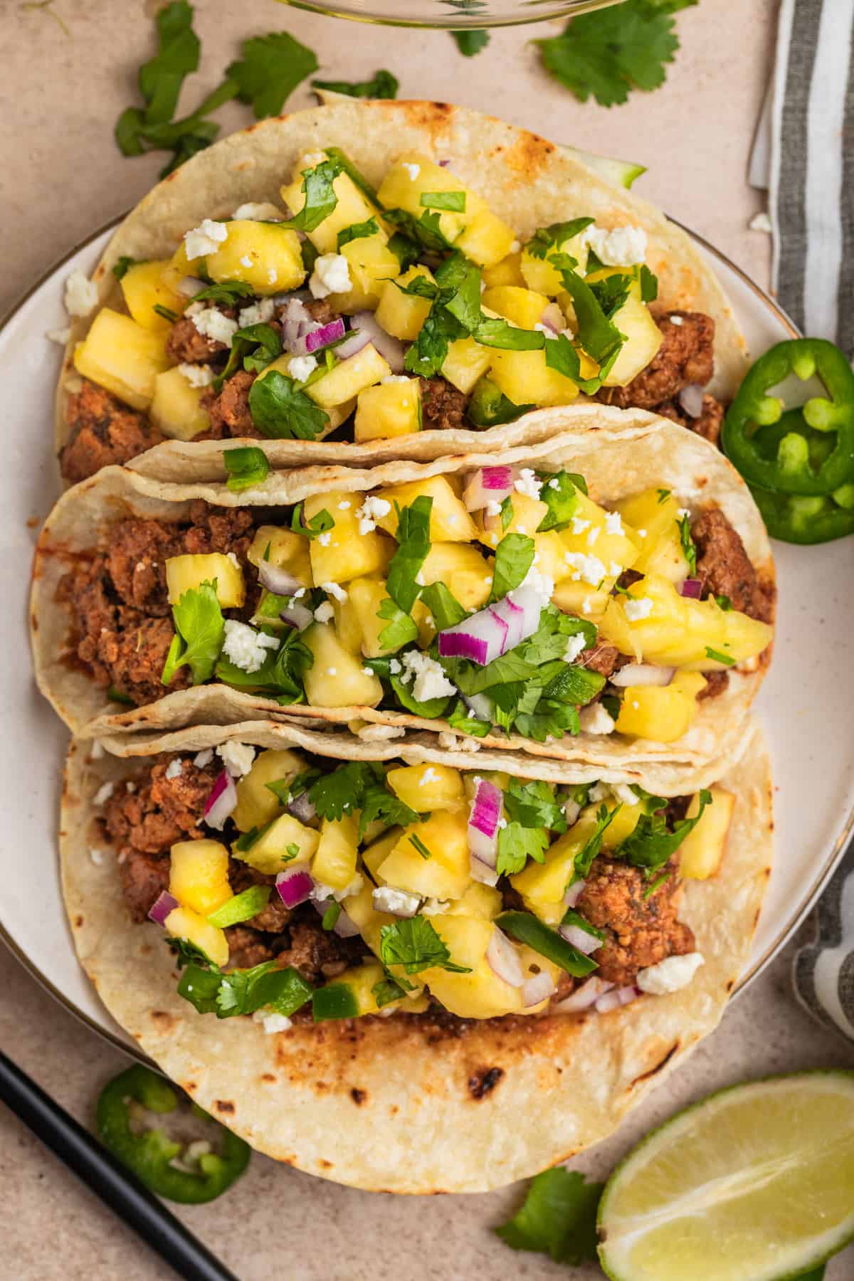 Overhead view of ground pork tacos topped with pineapple salsa.