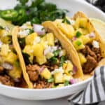 Ground pork tacos with pineapple salsa and cotija cheese on top.