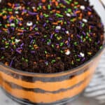 Trifle dish with layered Halloween dirt cake and Halloween sprinkles on top.