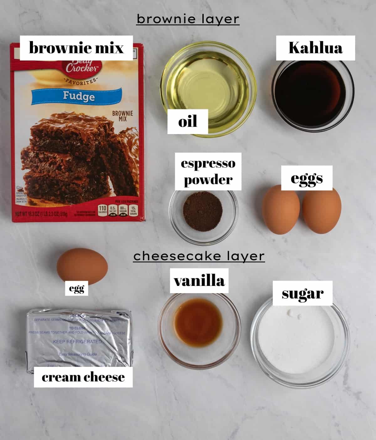 Brownie mix, eggs, cream cheese, sugar and other ingredients labeled on counter.