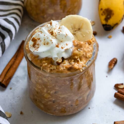 Pumpkin banana overnight oats in jar with whipped cream and cinnamon.