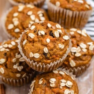 Pumpkin carrot muffins on wood tray with rolled oats on top.