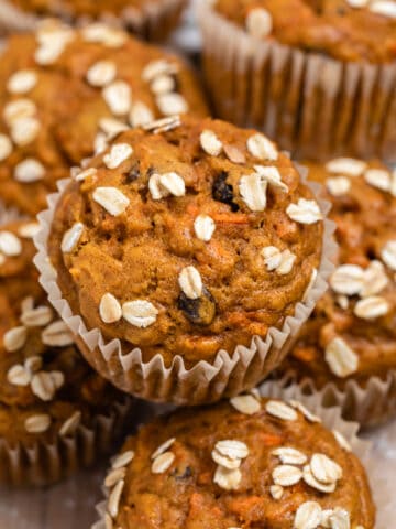 Pumpkin carrot muffins on wood tray with rolled oats on top.
