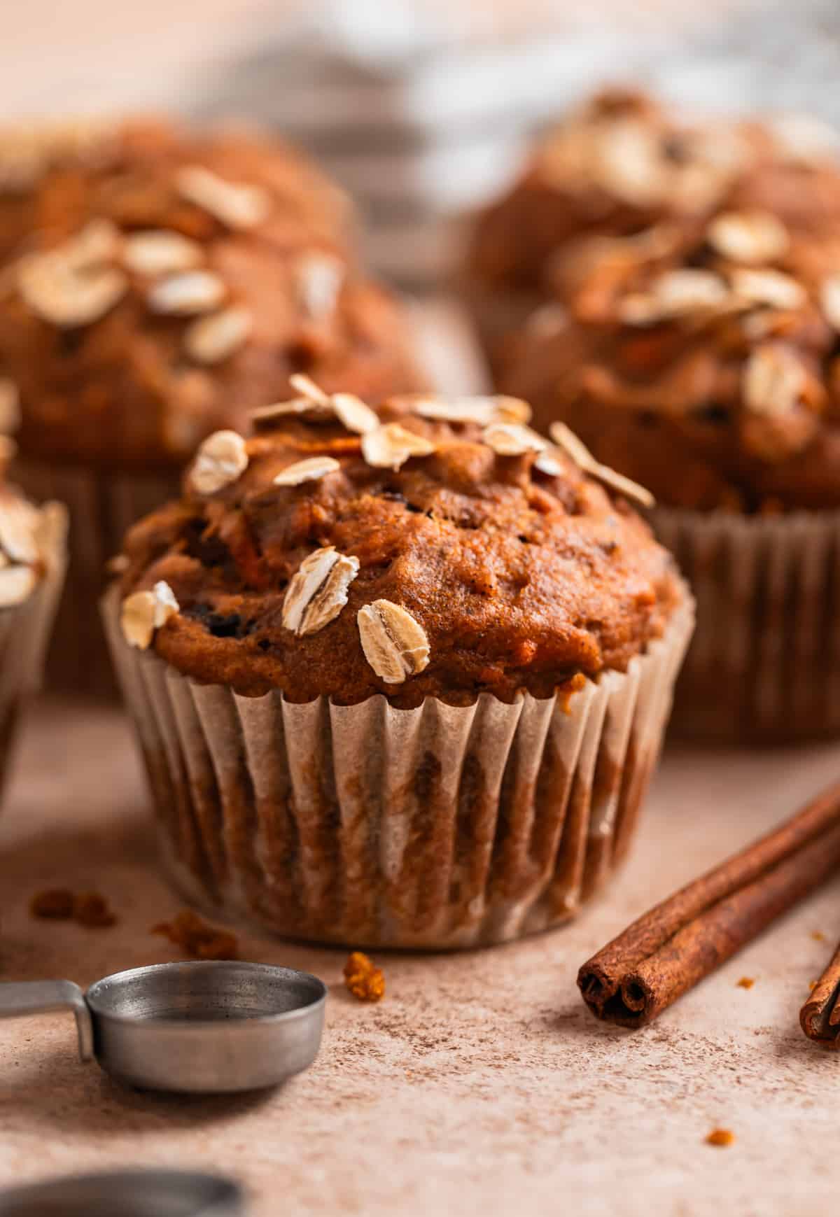 Pumpkin muffins with rolled oats on top and cinnamon sticks beside them.