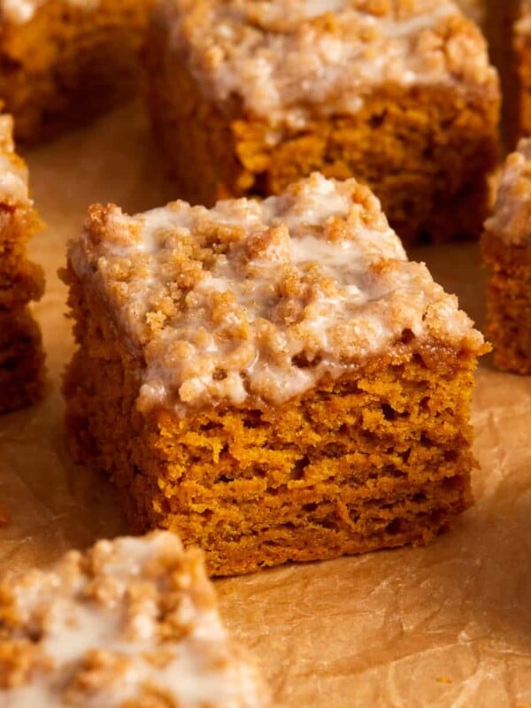 Slices of cinnamon streusel topped pumpkin coffee cake on crinkled brown parchment paper.