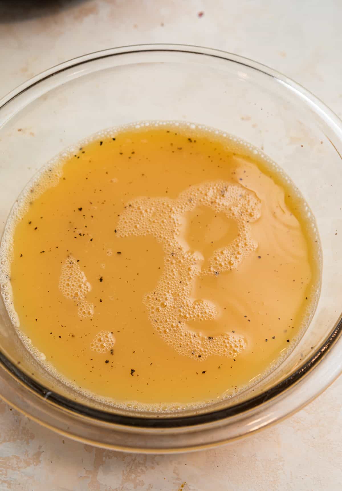 Wet ingredients mixture in glass mixing bowl for stuffing recipe.