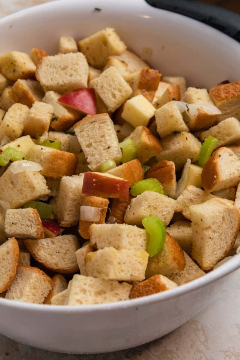 Cubed bread, celery, onion and apple in mixing bowl.