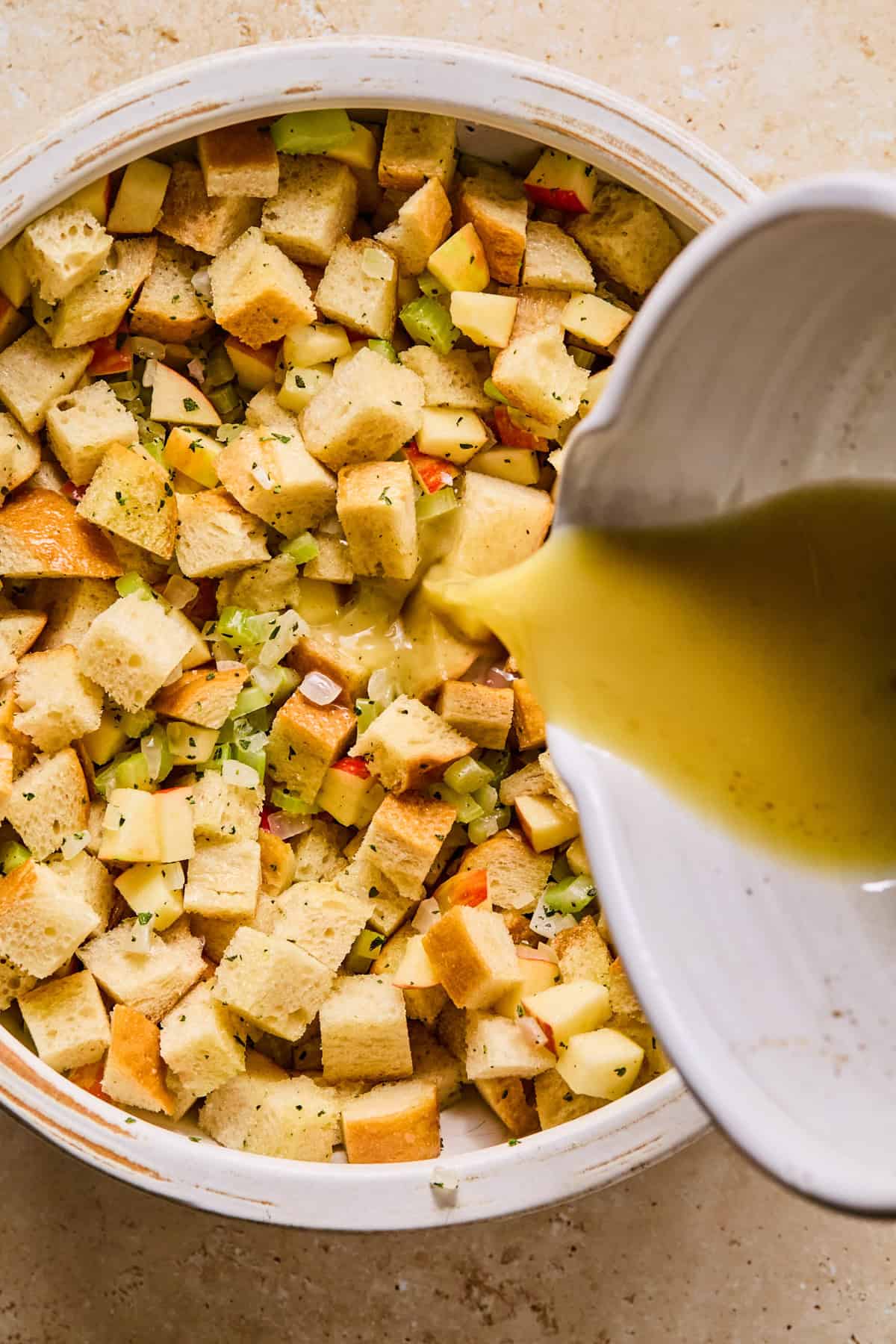 Broth mixture added to bowl with apple stuffing ingredients.