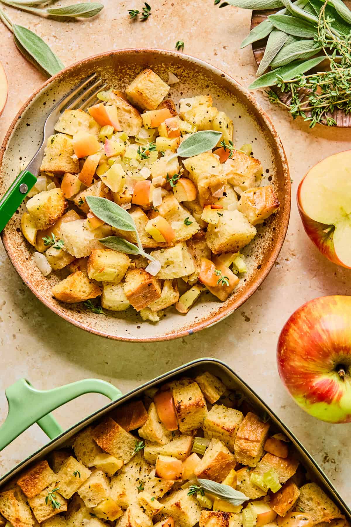Serving of apple sage bread stuffing on plate with pan nearby.