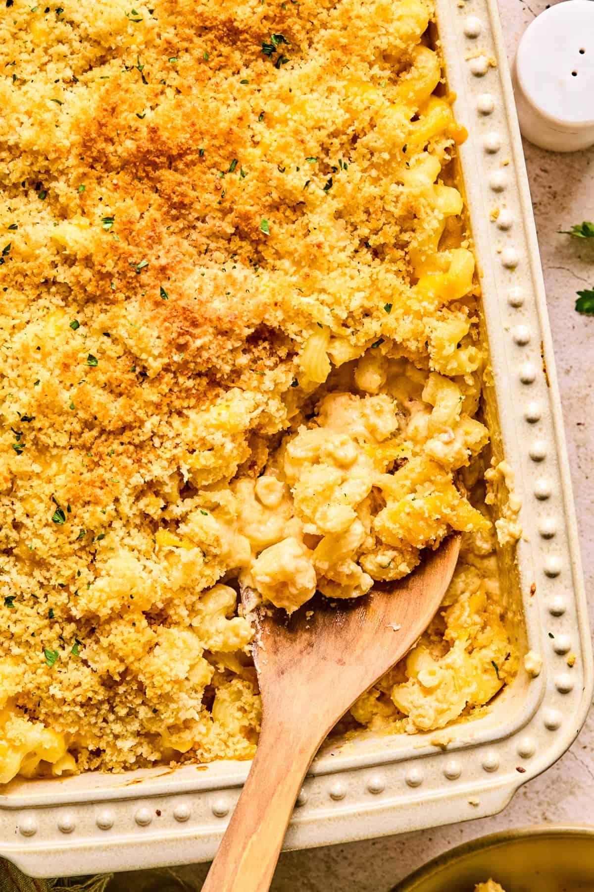 Cheddar gruyere macaroni and cheese in baking pan with spoon scooping into it.