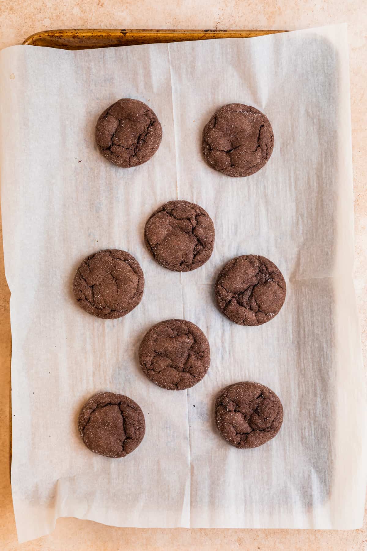 Baked chocolate cake mix cookies on parchment lined cookie sheet.
