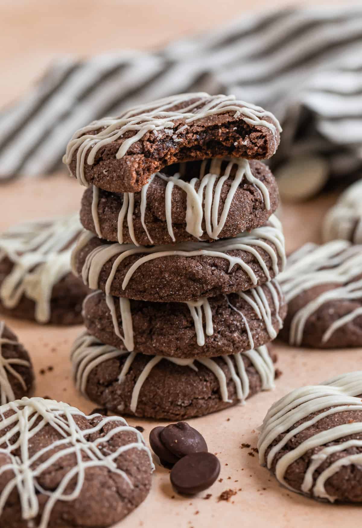 Stack of chocolate cake mix cookies with other cookies and chocolate chips surrounding.