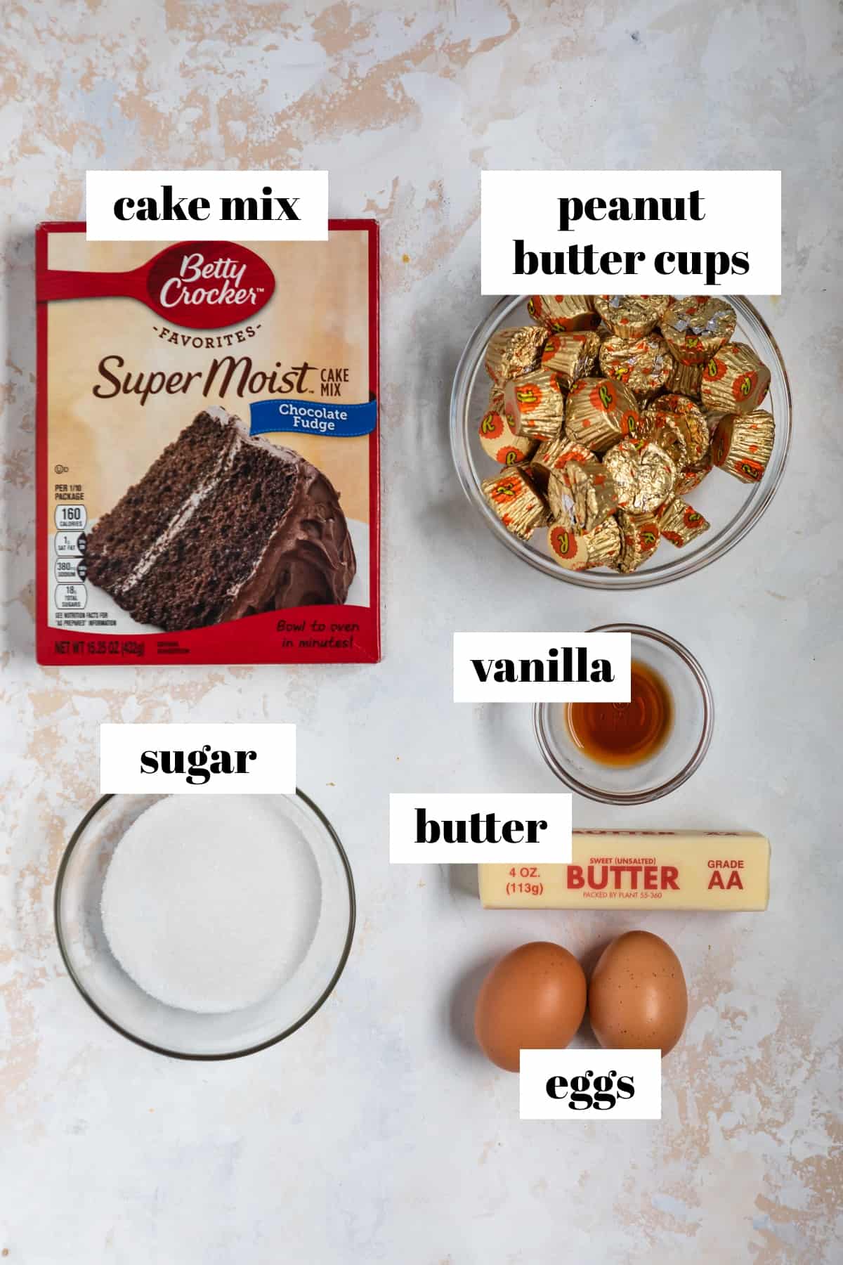 Eggs, sugar, reese cups, butter and other cookie ingredients labeled on counter.