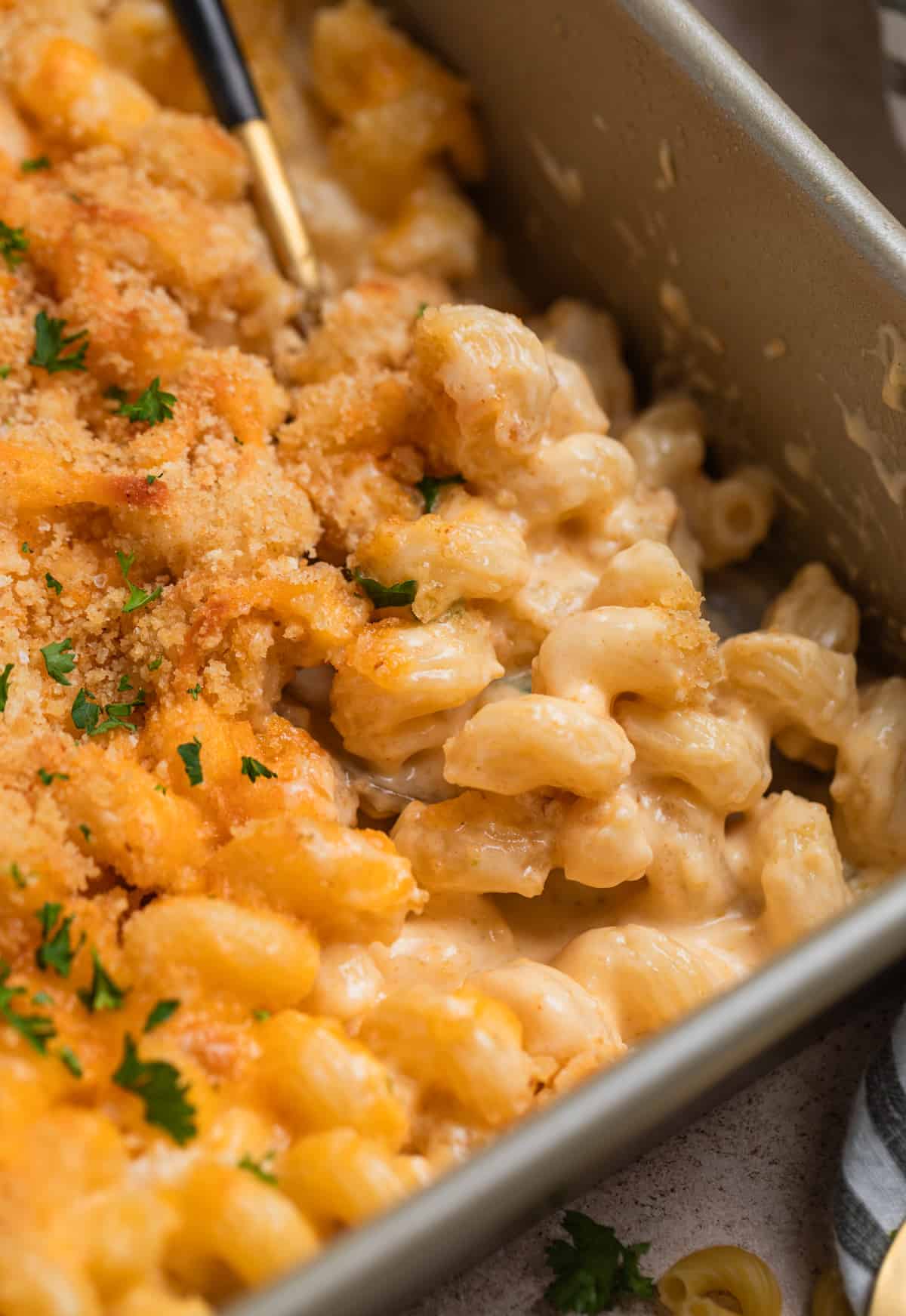 Pan with baked gruyere mac and cheese and spoon scooping in.