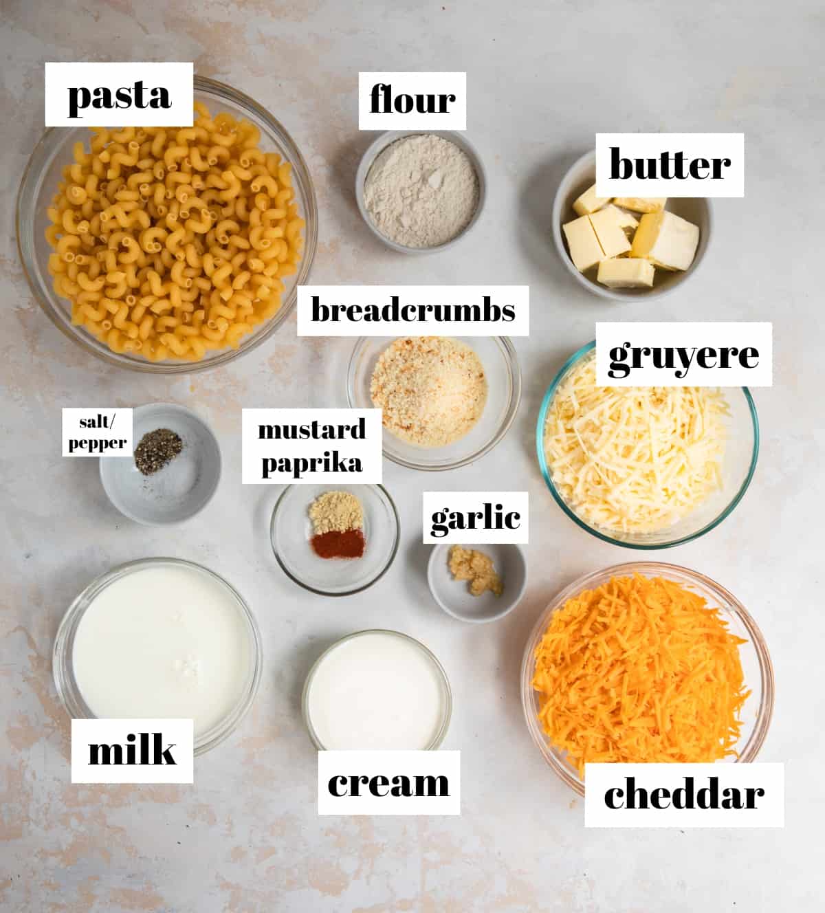 Pasta, flour, milk, cream, butter and other ingredients labeled on counter.