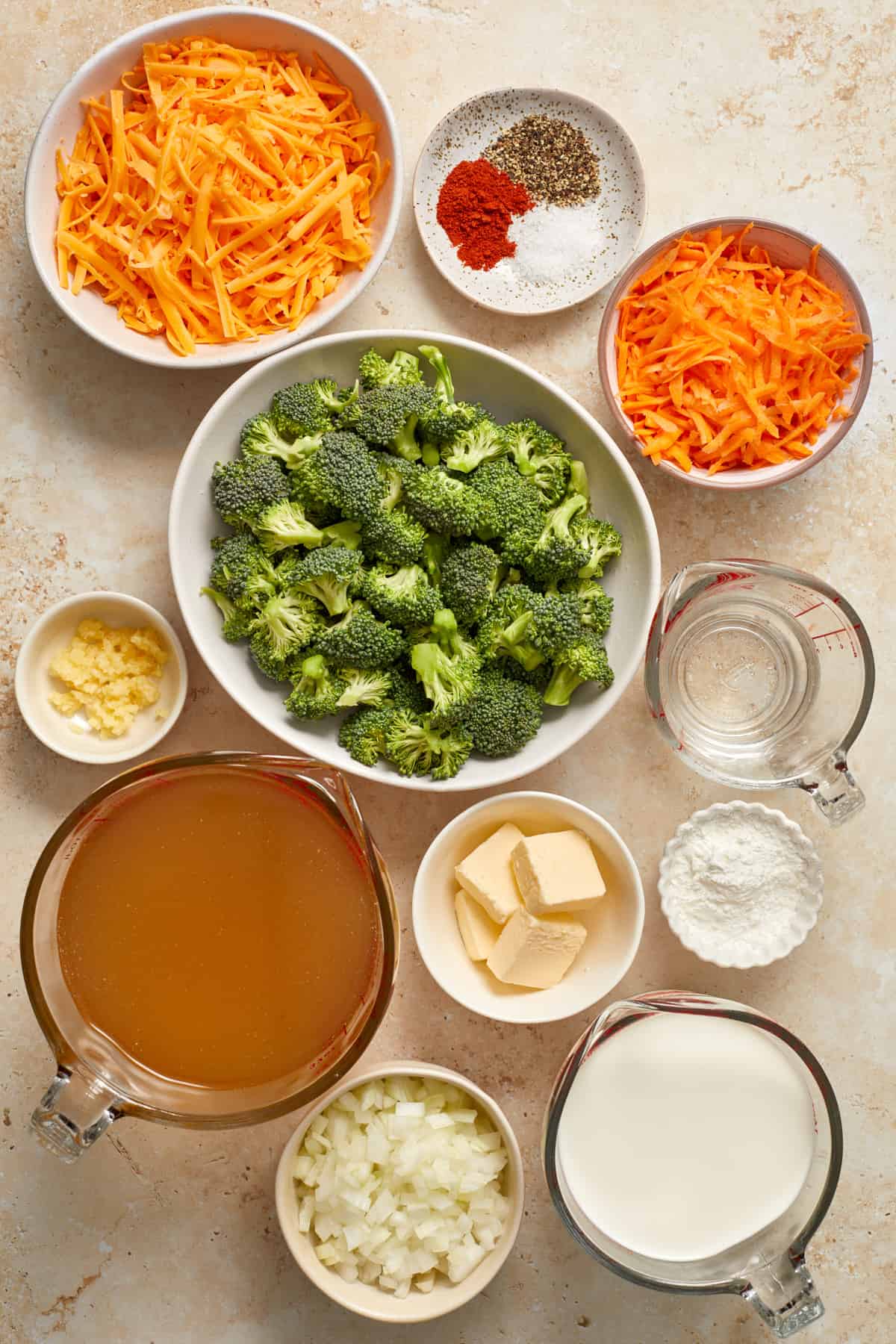 Carrots, cheese, butter, broth, broccoli and other soup ingredients arranged on surface to be used in recipe.