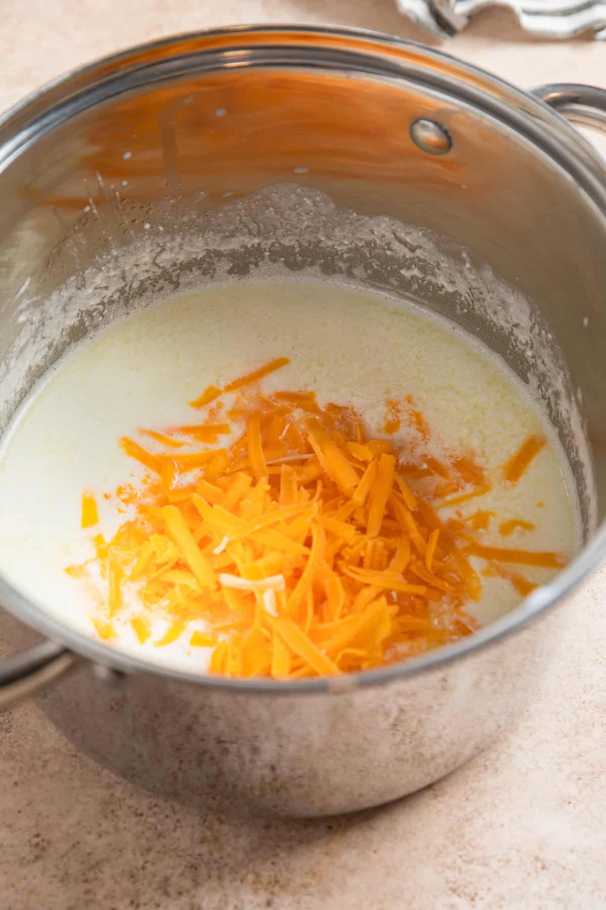 Greek yogurt, milk and shredded cheese in pot.