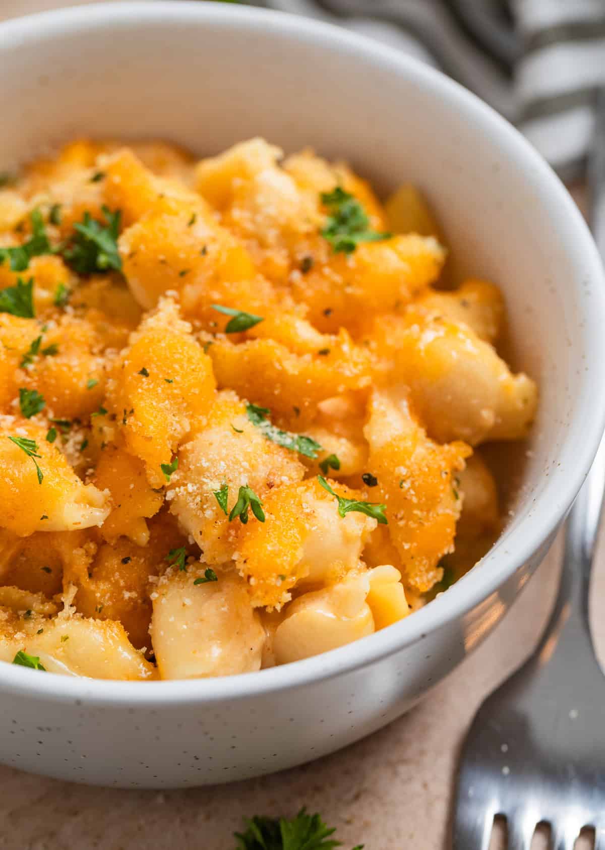 Protein macaroni and cheese in bowl topped with toasted breadcrumbs and parsley.