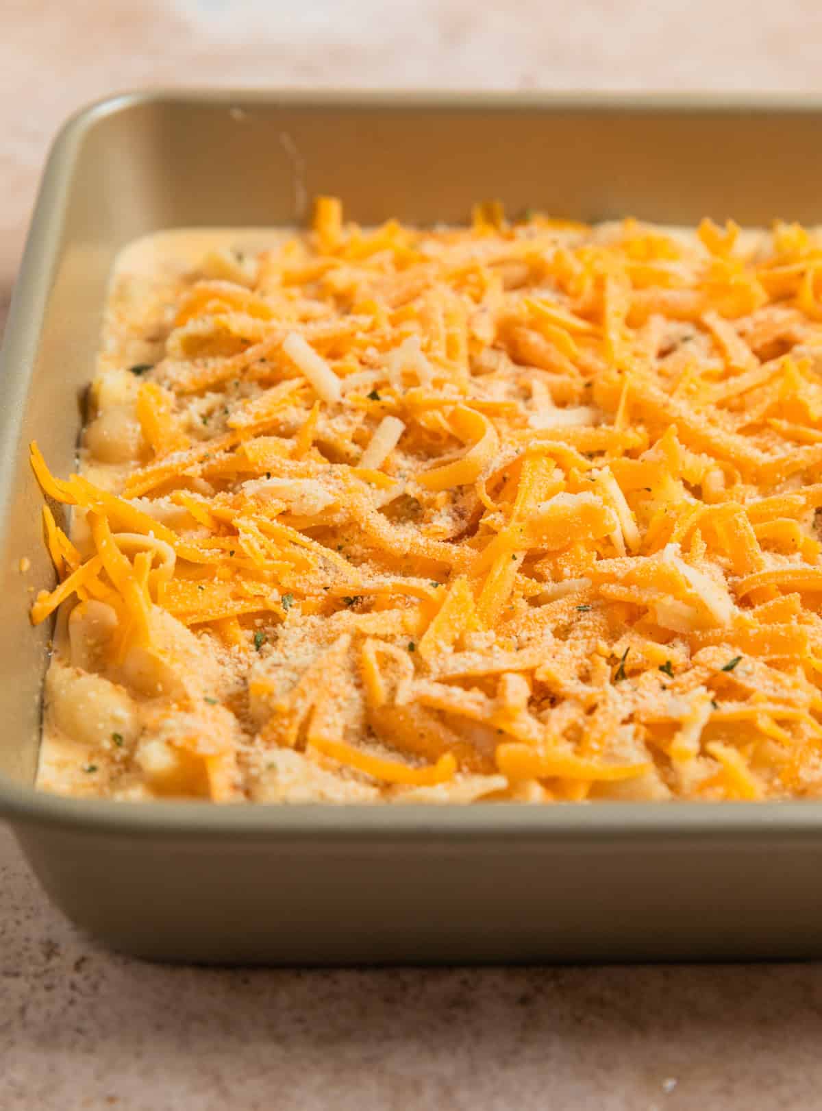 Shredded cheddar and white cheddar cheese on top of mac and cheese mixture.