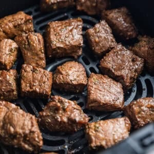 Cooked chunks of sirloin in air fryer basket.