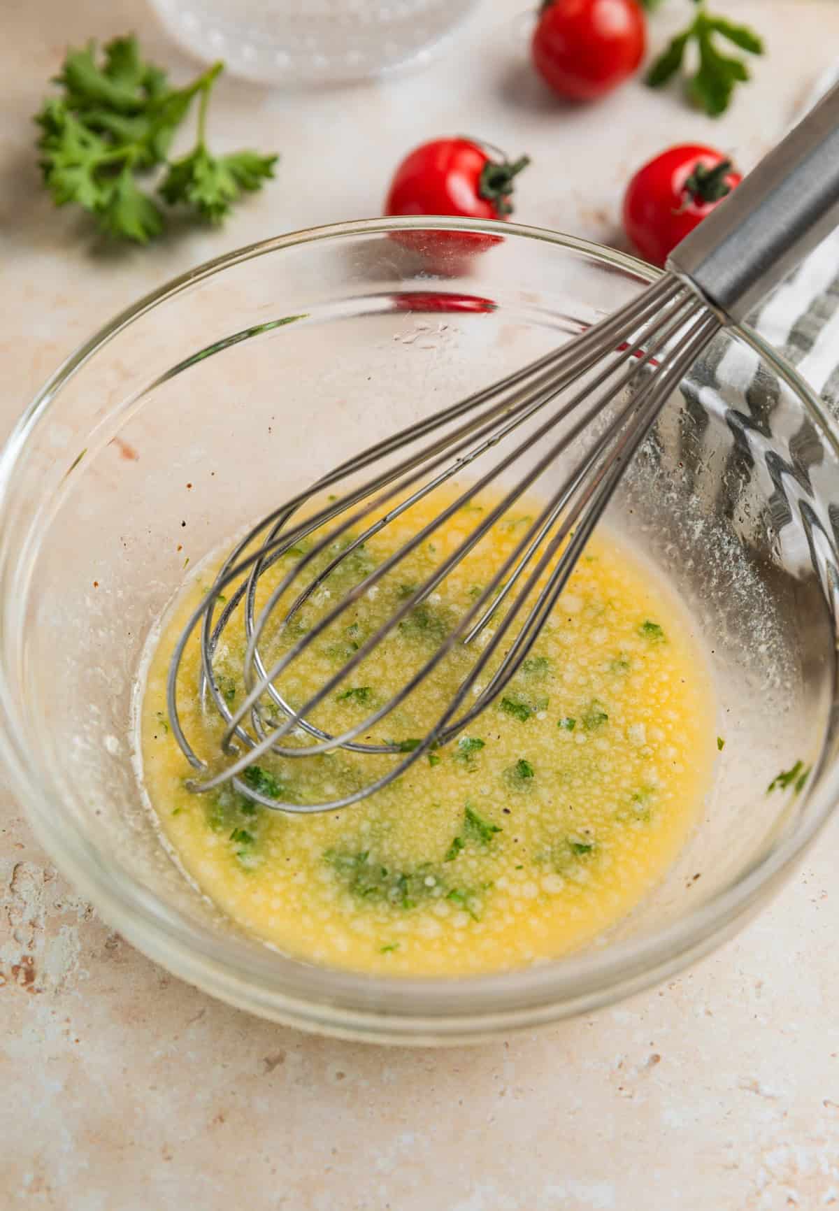 Lemon garlic butter sauce in glass bowl with whisk.