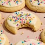 Eggless sugar cookies on surface with bite taken out of cookie.