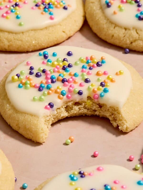 Eggless sugar cookies on surface with bite taken out of cookie.