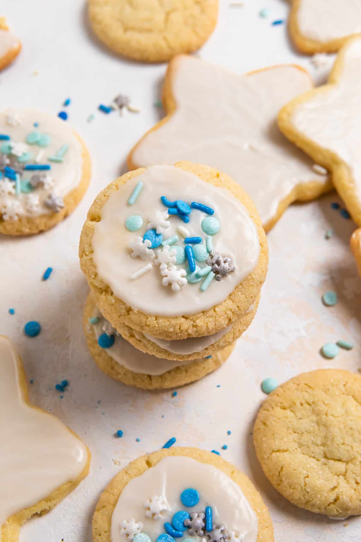 Stack of eggless sugar cookies with white icing and blue sprinkles.