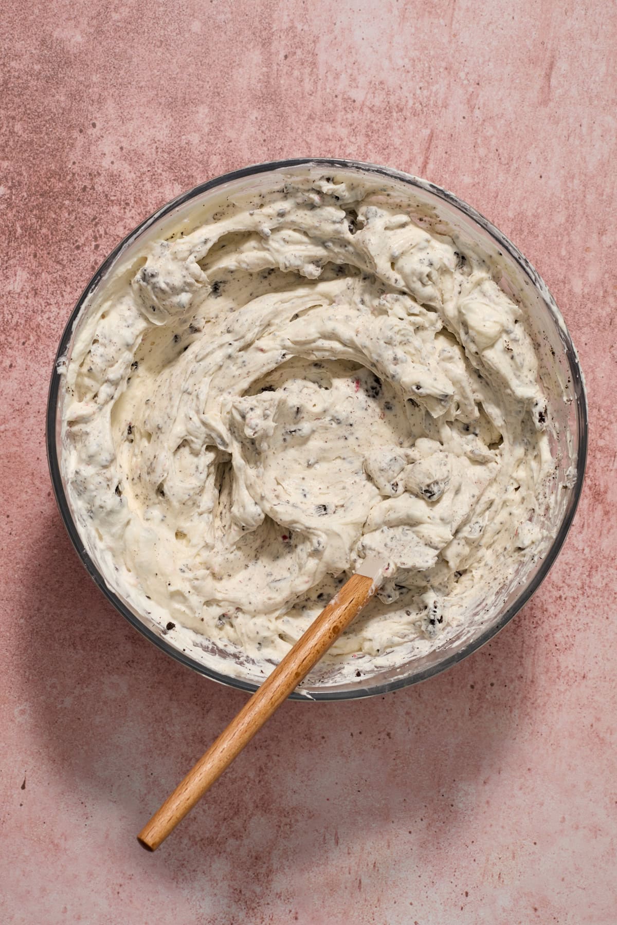 No bake peppermint Oreo cheesecake mixture in glass bowl with spatula.