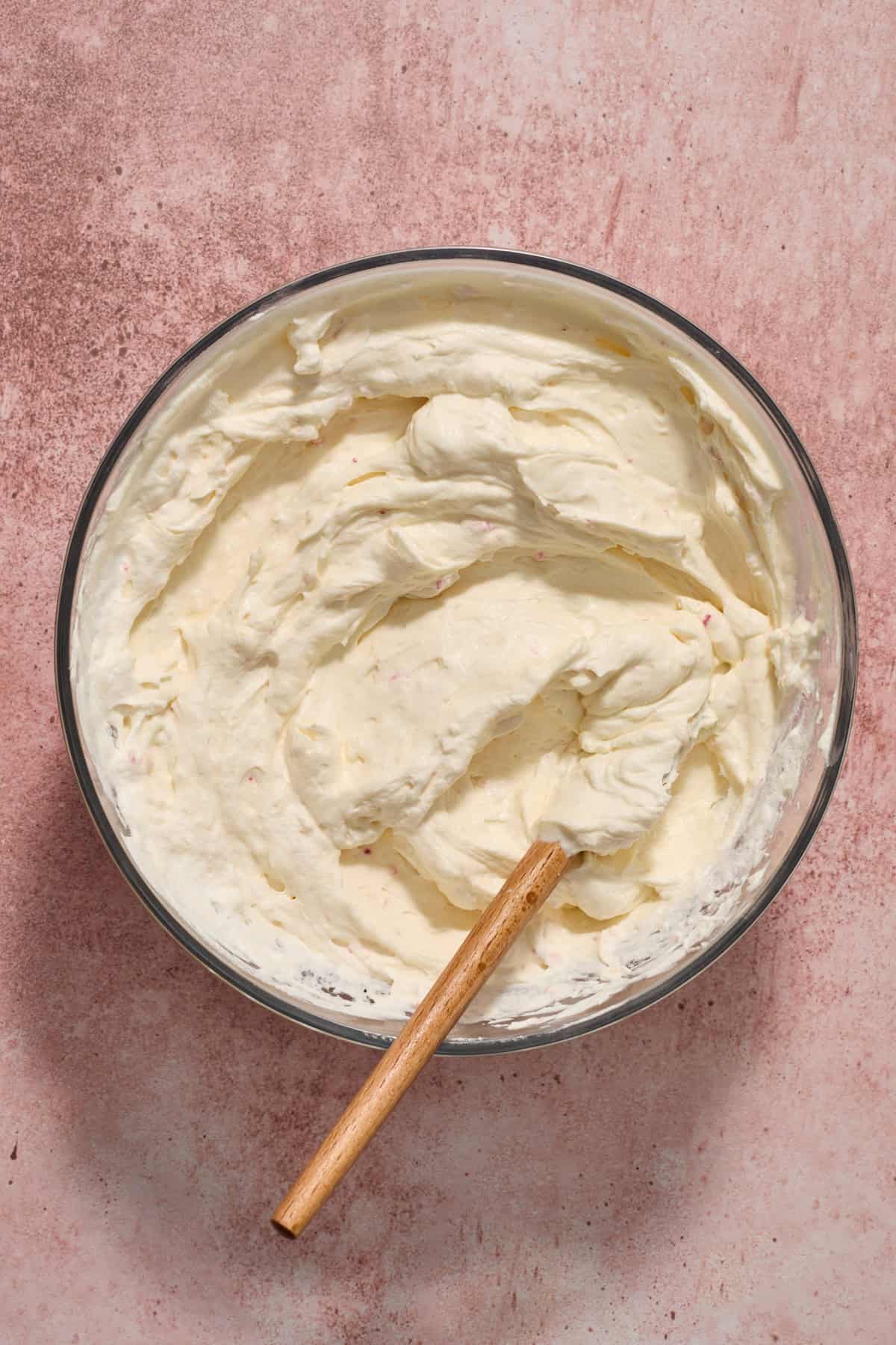 Crushed peppermints and whipped cream folded into cream cheese mixture in bowl with spatula.