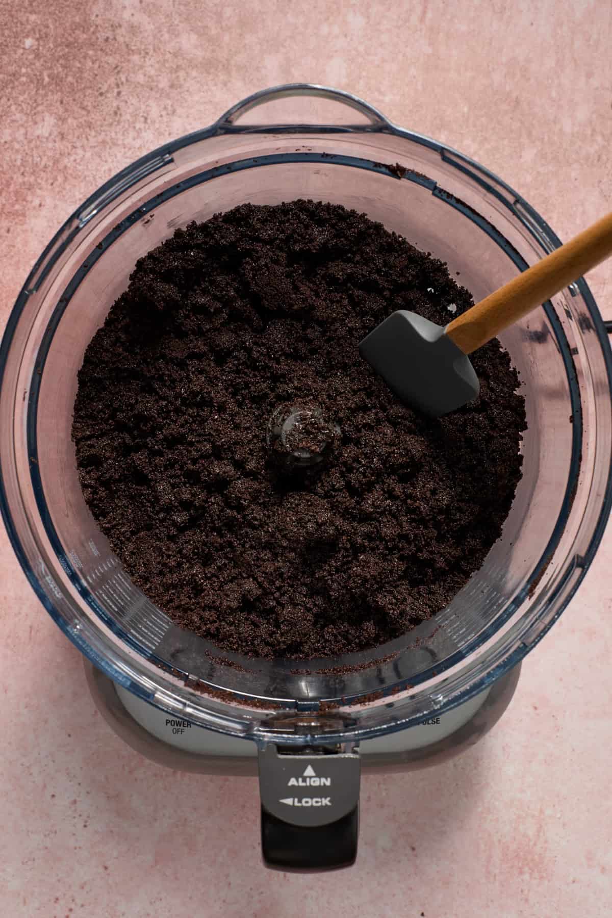 Chocolate cookie pie crust prepared in food processor with spatula.