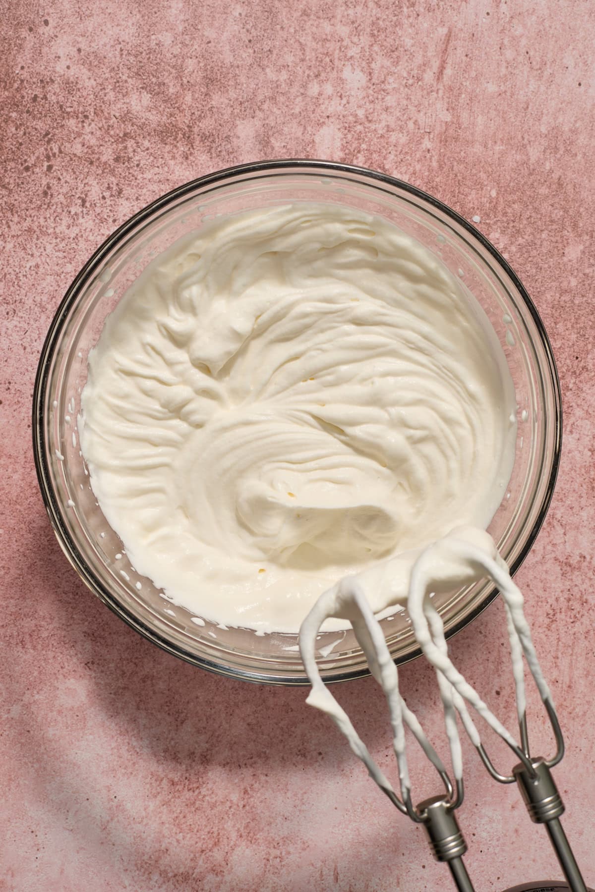 Heavy whipping cream whipped to stiff peaks in mixing bowl.