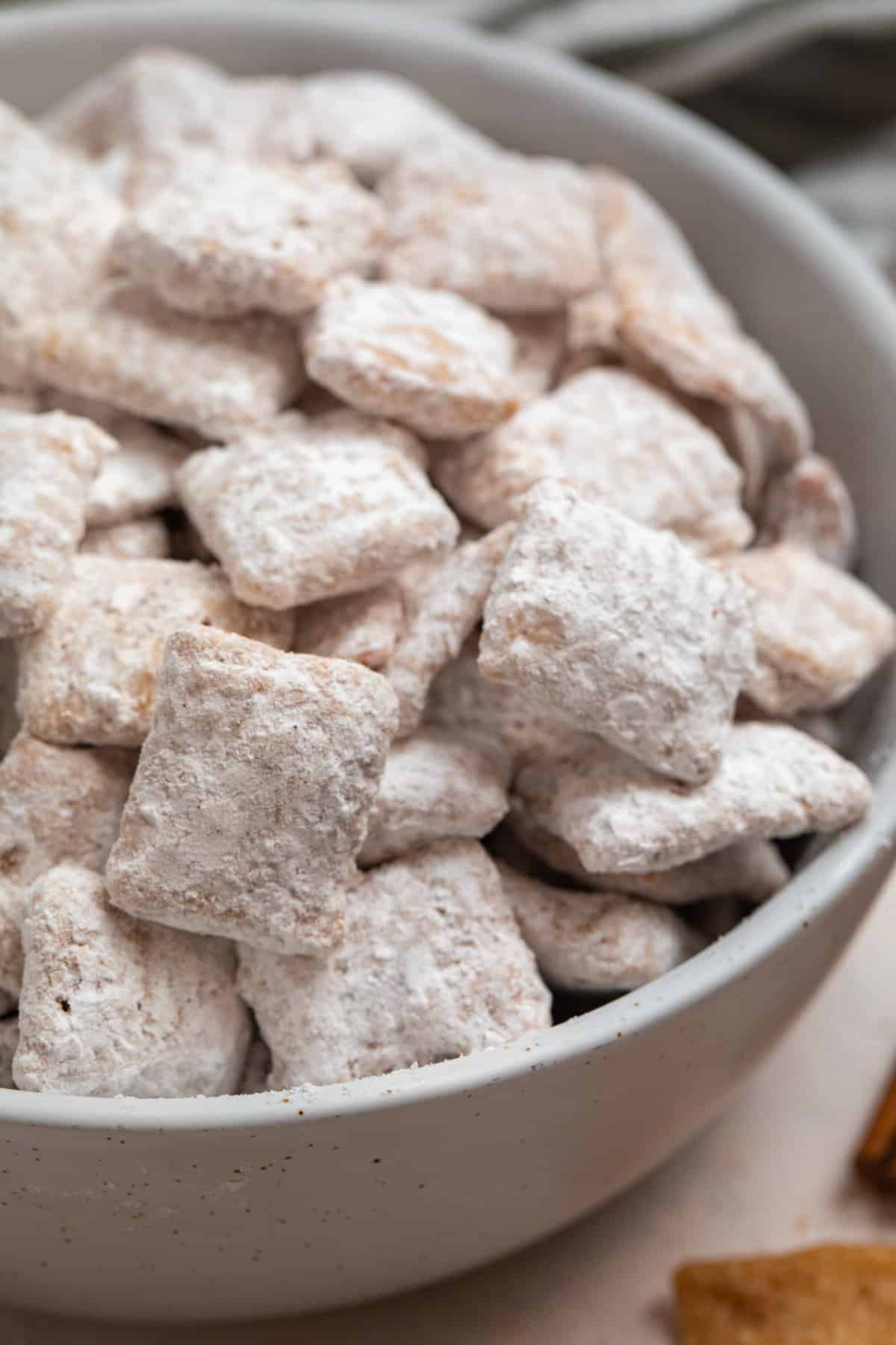 Bowl of cinnamon chex mix with powdered sugar.
