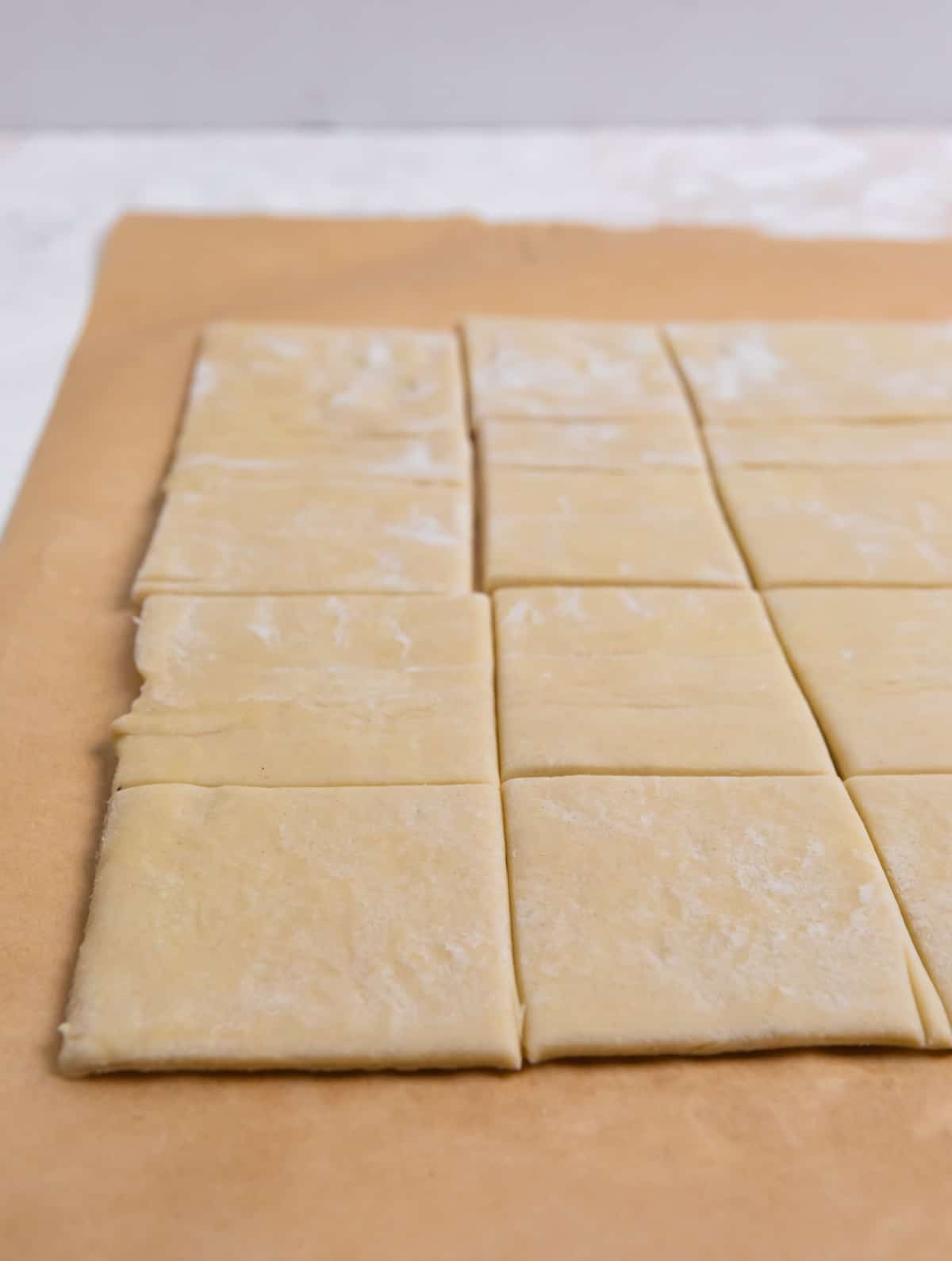 Puff pastry dough on parchment sliced into squares.
