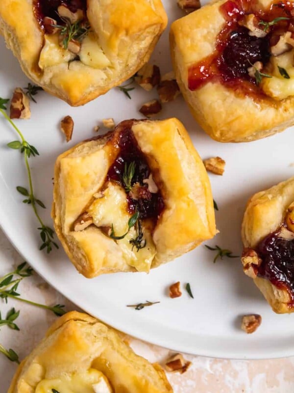 Overhead view of puff pastry baked brie bites on white plate.