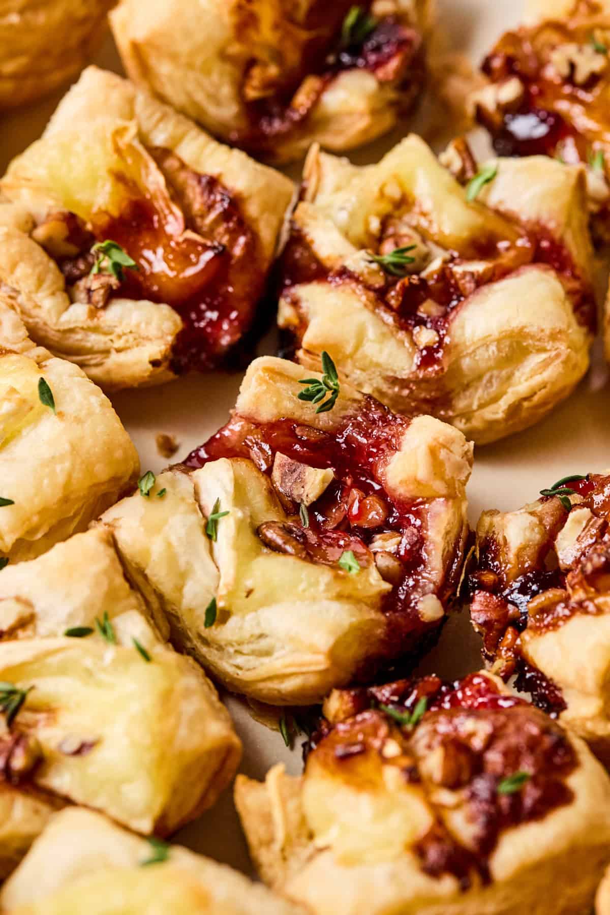 Puff pastry brie bites on plate topped with fresh thyme.