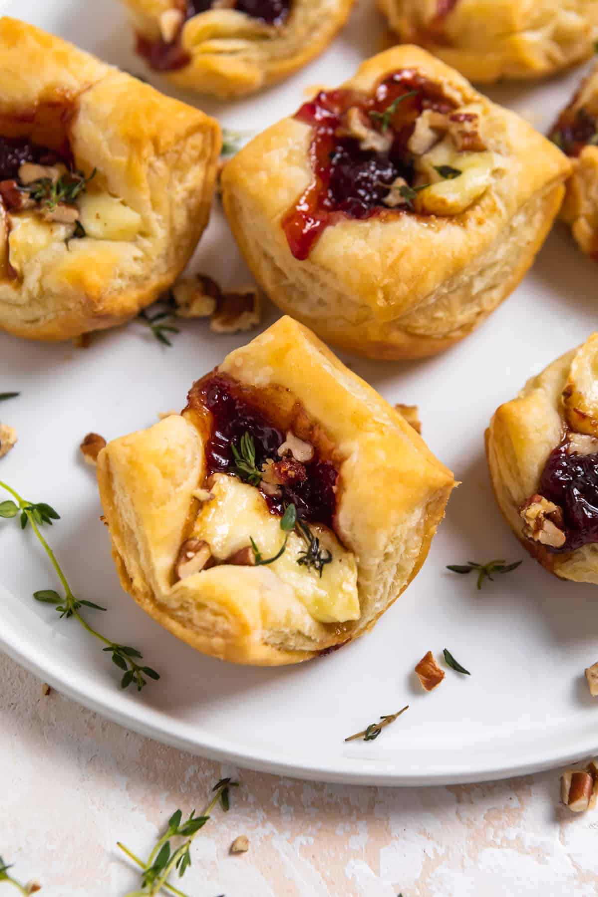 Puff Pastry Brie Bites on white plate with fresh thyme.