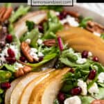 Roasted pear salad in white bowl with goat cheese, pecans and pomegranate.